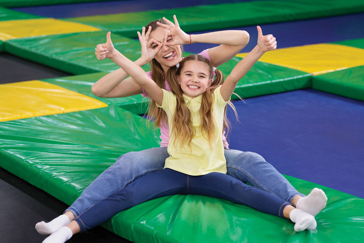 Two girls making silly faces sitting on a trampoline