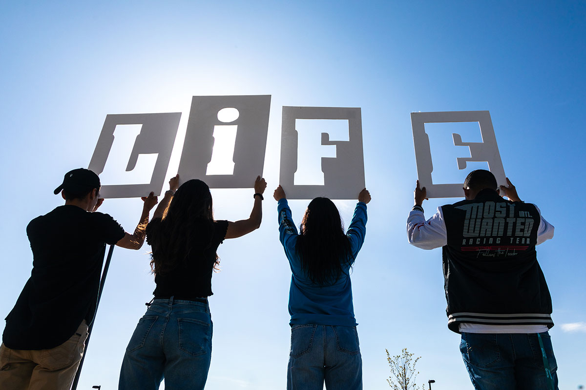 Group of students holding up cut out letters of L I F E