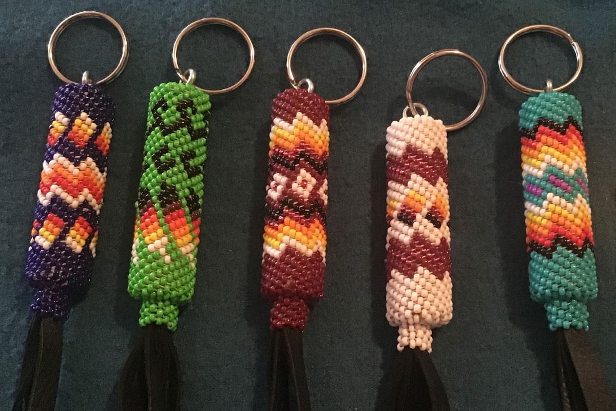 Five keychains with traditional Native American beadwork in greens, orange, red, pink with tassels