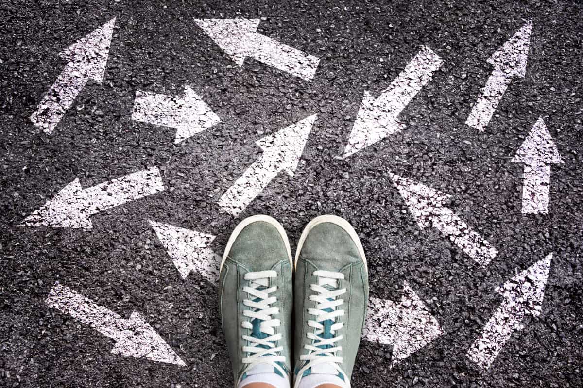 A person in sneakers with chalk drawn arrows pointing in multiple directions.