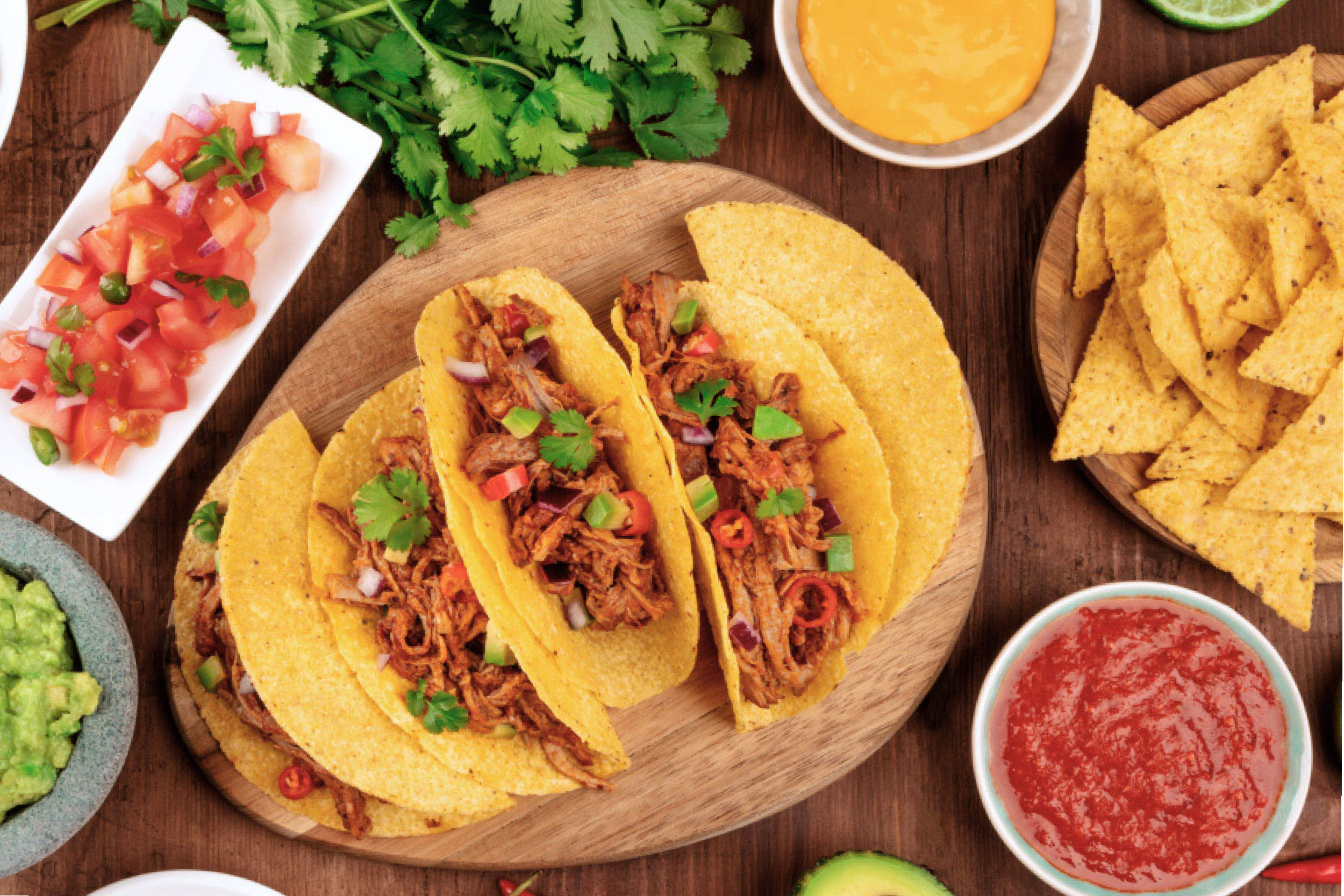 Three tacos, chopped tomatoes, salsa and cilantro