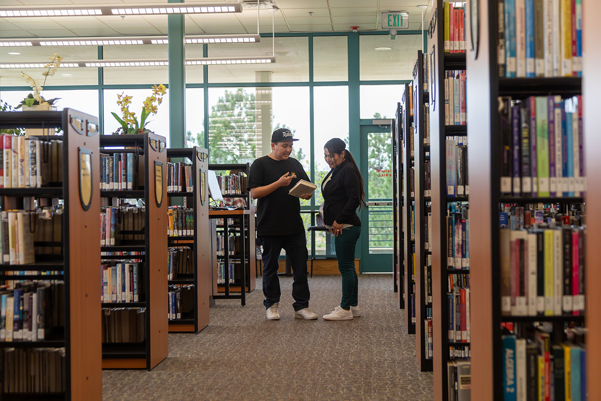 Two students in the SJC library looking at a book