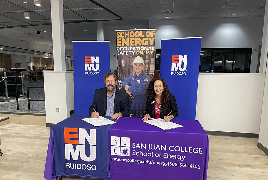 SJC President Dr. Pendergrass and ENMU President Trosper at table with ENMU, SJC, and School of Energy banners signing papers