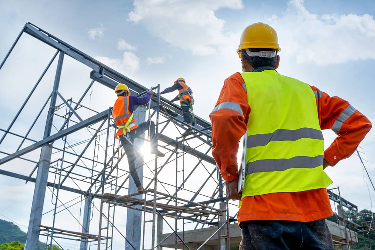 A San Juan College student watching two other students working on a steel frame for a building