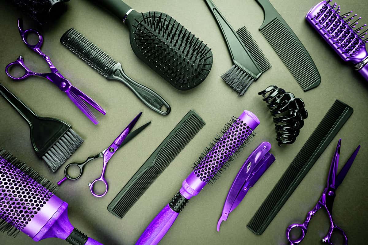 salon tools on a flat surface background, combs, brushes, scissors, curling irons.