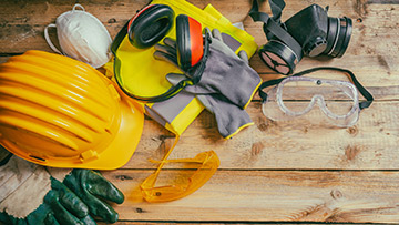 Hand hat, ear protection and other tools on a tabletop.