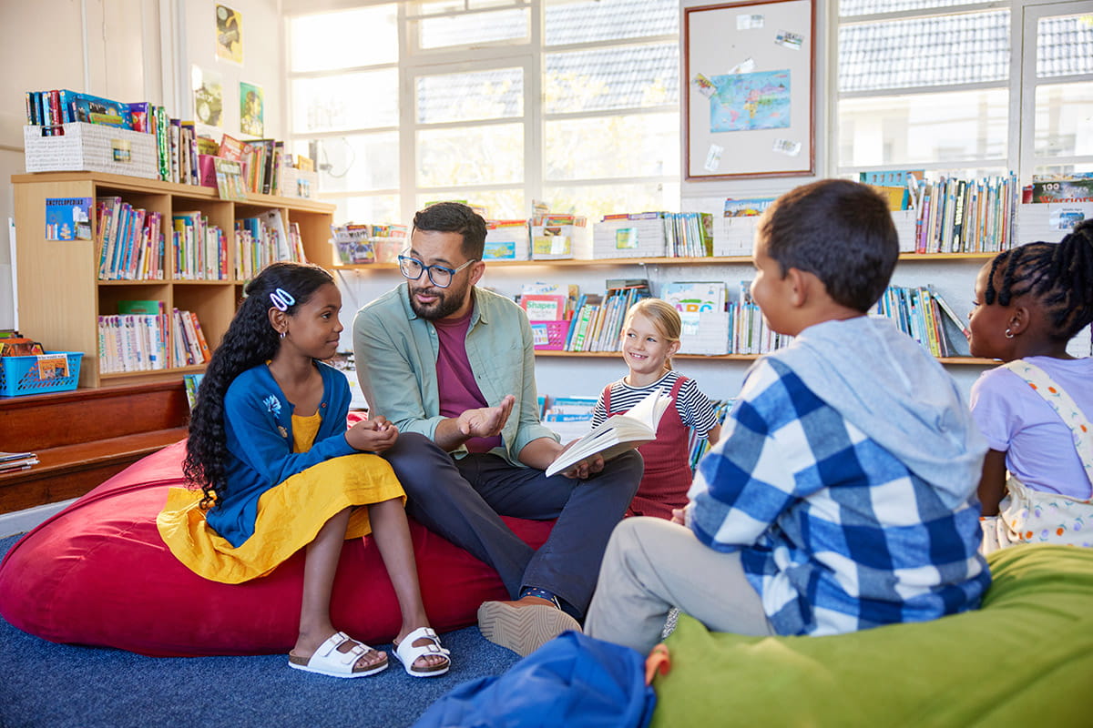 A male teacher in a classroom setting with four students in San Juan College's Teacher Residency Program.