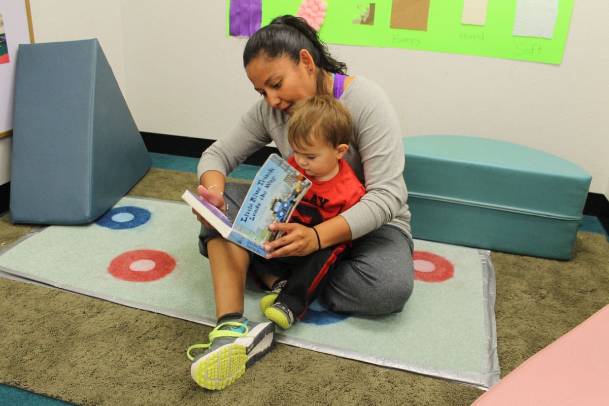An SJC Child and Family Development Center Instructor reading to a toddler in the Toddler Classroom