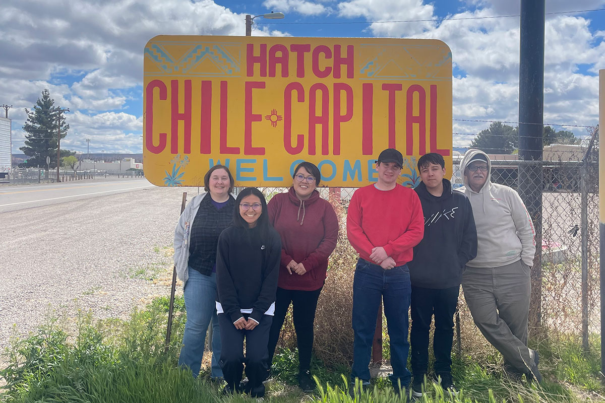 SJC TRIO Students standing in front of the yellow and red Hatch Chile-Capital sign